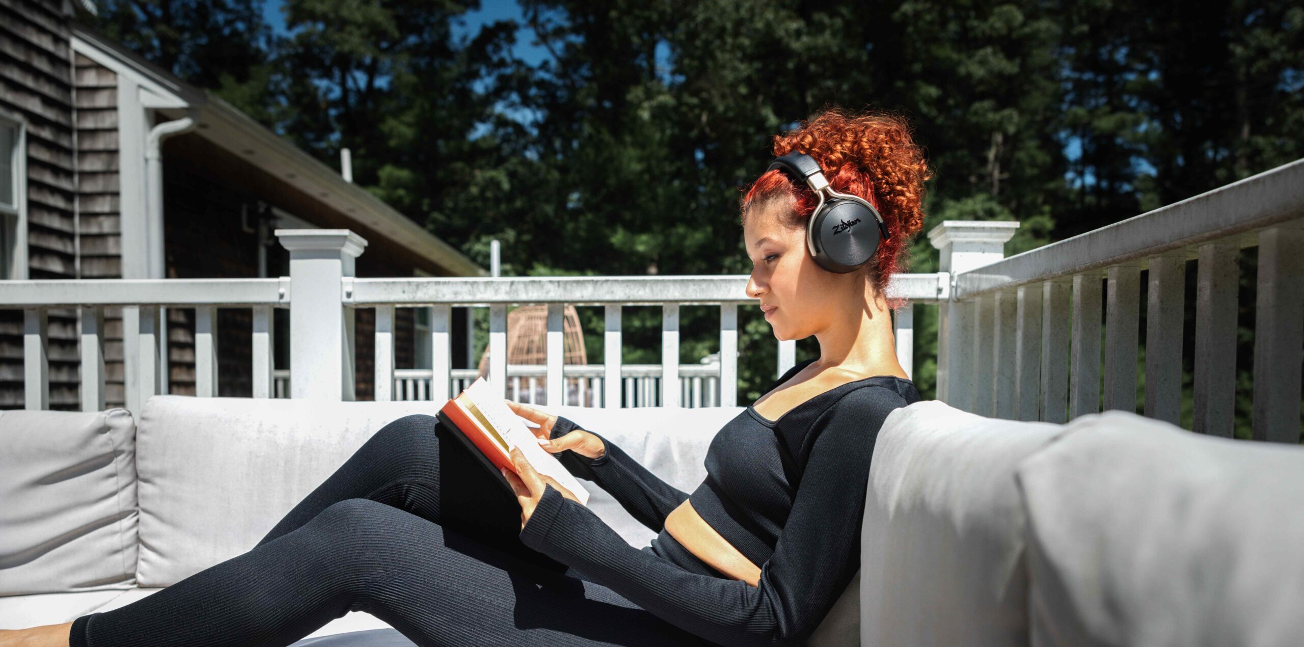 Zildjian alchem-e headphones in black. User reading and utilising noise cancelling feature.